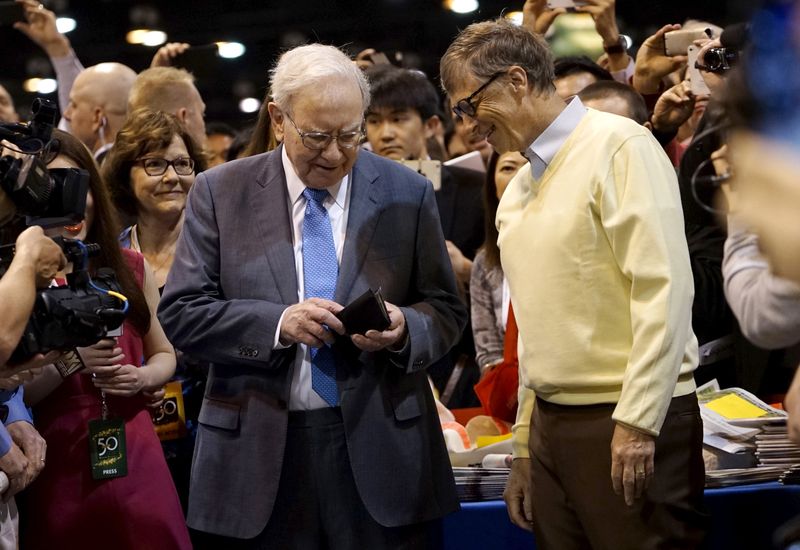 Berkshire Hathaway CEO Warren Buffett (L) gets his wallet out to pay a bet to Microsoft co-founder Bill Gates after participating in a newspaper throwing contest prior to the Berkshire annual meeting in Omaha, Nebraska May 2, 2015.  REUTERS/Rick Wilking