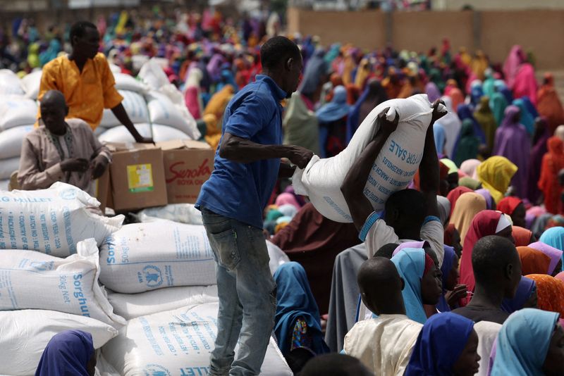 FILE PHOTO: Camp workers offload sorghum at open field as beneficiaries from different Internally Displaced Persons camps wait to receive support following the exit of USAID, at a World Food Programme distribution centre in Dikwa, Borno State, Nigeria, August 27, 2025. REUTERS/Sodiq Adelakun./File Photo