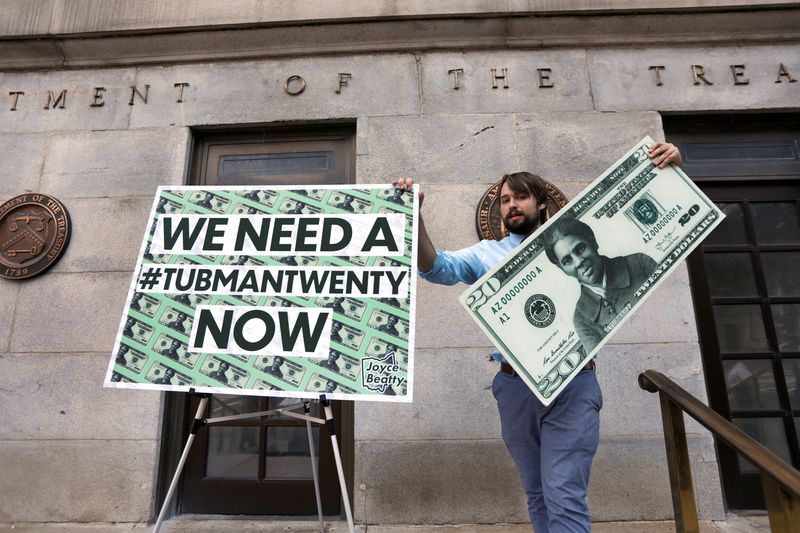 FILE PHOTO: Capitol Hill staff member places signs before a news conference by House Majority Leader Steny Hoyer (D-MD) on Treasury Secretary Steve Mnuchin's decision to indefinitely delay putting famous abolitionist Harriet Tubman on the new $20 bill, on the steps of the Treasury Department in Washington, U.S., June 27, 2019. REUTERS/Yuri Gripas/File Photo