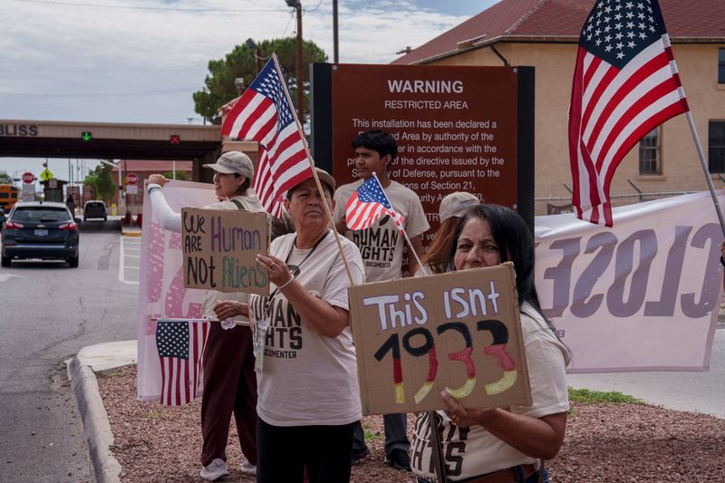 FILE PHOTO: Protesters opposing mass deportations by ICE hold signs during a protest held at the Cassidy Gate at Fort Bliss, the U.S. Army base where a large new ICE detention facility is being built, in El Paso, Texas, U.S., August 17, 2025.  REUTERS/Paul Ratje/File Photo