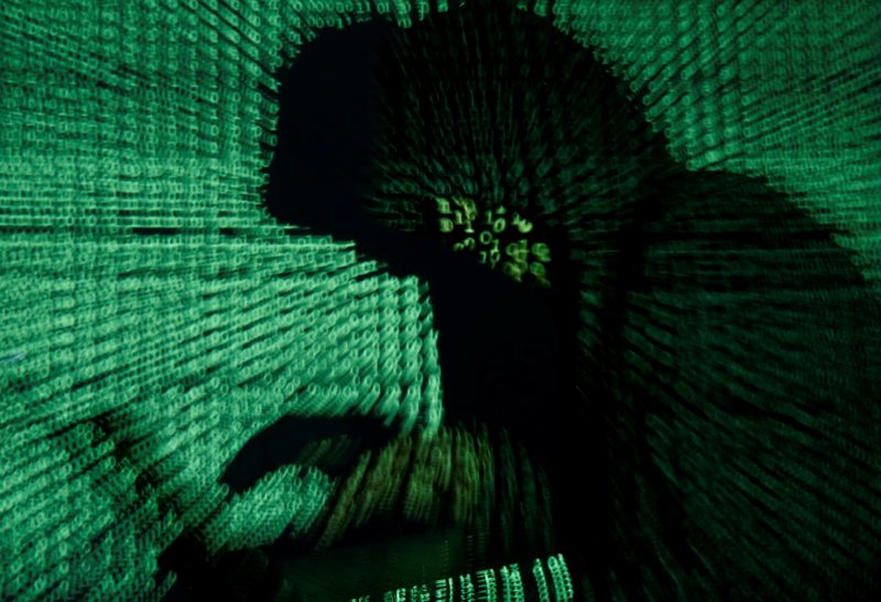 FILE PHOTO: A man holds a laptop computer as cyber code is projected on him in this illustration picture taken on May 13, 2017. REUTERS/Kacper Pempel/Illustration/File Photo