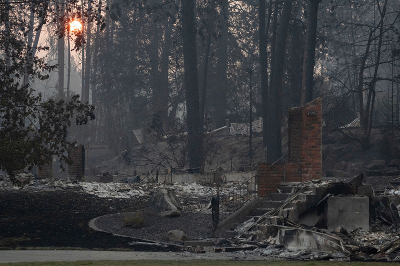 An orange sun at sunrise in the background of a burned home during the Old Trails fire in Spokane, Washington, U.S., August 4, 2026. REUTERS/Matt Mills McKnight