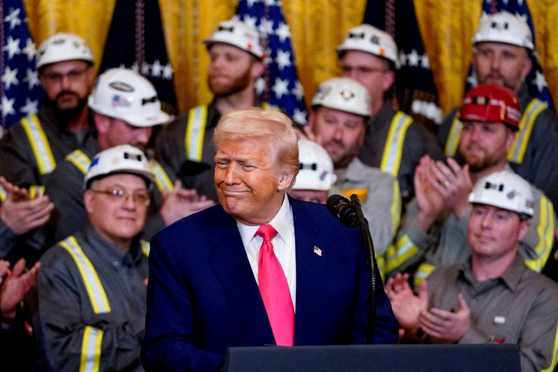FILE PHOTO: U.S. President Donald Trump reacts next to coal industry workers, on the day he signs energy-related executive orders at the White House in Washington, D.C., U.S., April 8, 2025. REUTERS/Nathan Howard//File Photo