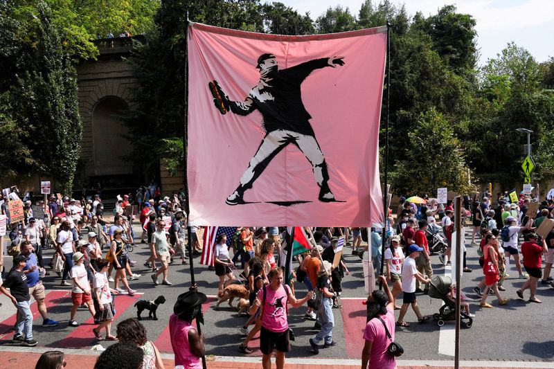 FILE PHOTO: Demonstrators hold a banner inspired by the work of artist Banksy, showing a masked protester throwing a sandwich, as they attend a "We Are All DC" march, in Washington, D.C., U.S., September 6, 2025. REUTERS/Leah Millis/File Photo