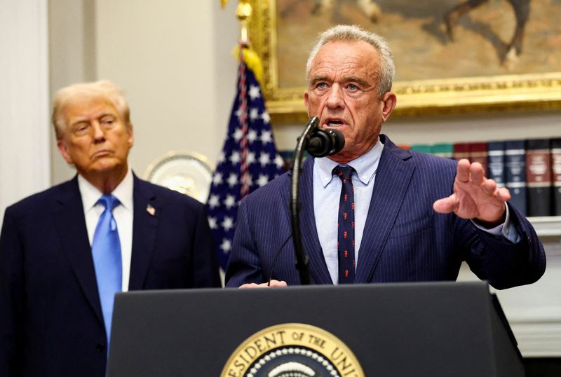 FILE PHOTO: U.S. Secretary of Health and Human Services Robert F. Kennedy Jr. delivers remarks while U.S. President Donald Trump listens during a press conference to announce a link between autism and childhood vaccines and the use of popular pain medication Tylenol for pregnant women and children, claims which are not backed by decades of science, at the White House, in Washington, D.C., U.S., September 22, 2025. REUTERS/Kevin Lamarque/File Photo