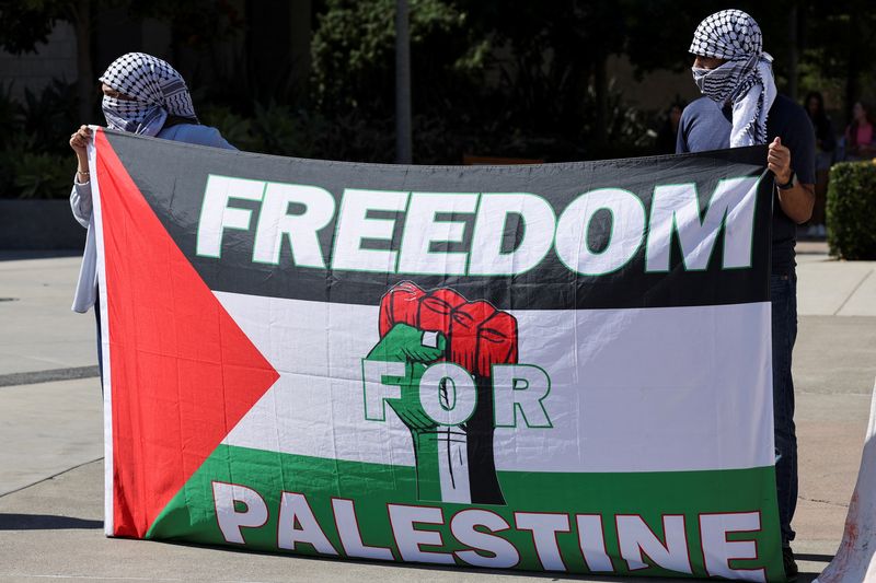 People hold a banner, as students walkout of classes in what they call "one year of genocide on the people of Gaza", as they demonstrate at the University of California,  in Irvine, California, U.S. October 7, 2024.   REUTERS/Mike Blake