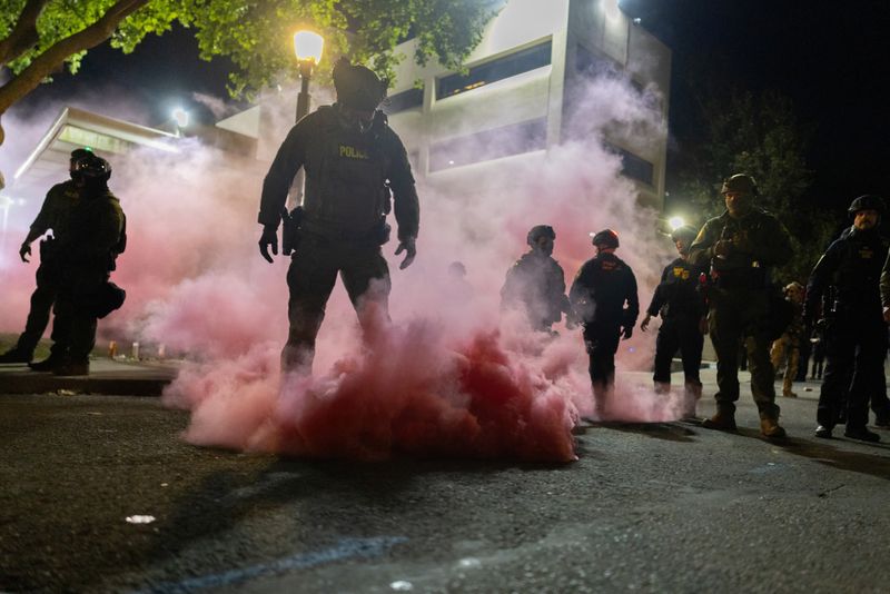 Law enforcement officers deploy smoke grenades to disperse protesters gathered outside the U.S. Immigration and Customs Enforcement (ICE) headquarters in south Portland, Oregon, U.S., October 5, 2025. REUTERS/Carlos Barria