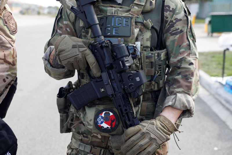 FILE PHOTO: A U.S. Immigration and Customs Enforcement officer holds a weapon during a protest outside an ICE facility, weeks after President Donald Trump ordered increased federal law enforcement presence and stepped-up immigration enforcement actions by the Department of Homeland Security, in Broadview, Illinois, U.S., September 12, 2025.  REUTERS/Octavio Jones/File Photo