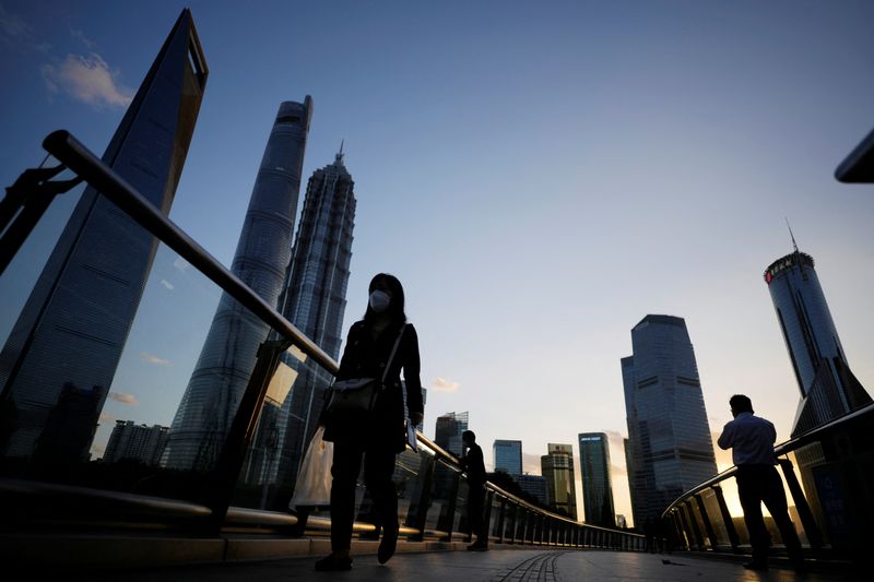 FILE PHOTO: People walk on an overpass past office towers in the Lujiazui financial district of Shanghai, China October 17, 2022. REUTERS/Aly Song/File Photo
