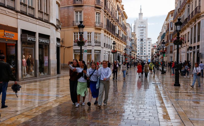 Tourists walk along a shopping street in central Malaga, Spain, April 28, 2022. REUTERS/Jon Nazca