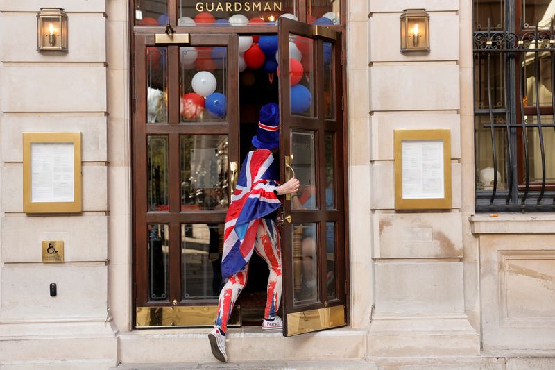 FILE PHOTO: A woman draped in a Union Jack flag enters a restaurant in London, Britain, May 7, 2023. REUTERS/Piroschka Van De Wouw/ File Photo