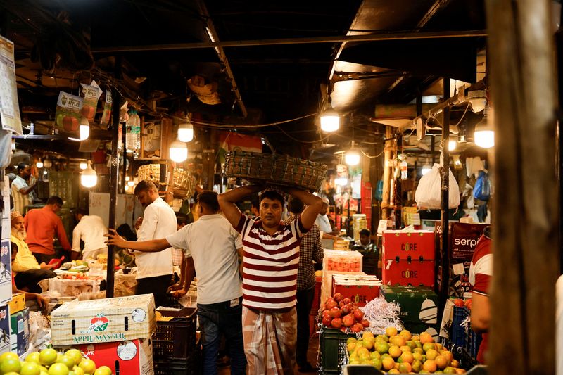 FILE PHOTO: A man carries fruits inside a wholesale market in Mumbai, India, March 19, 2025. REUTERS/Francis Mascarenhas/File Photo