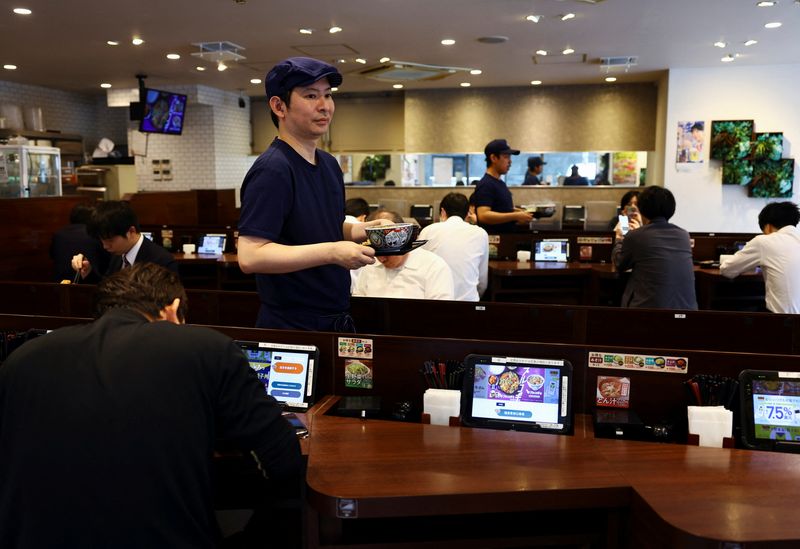 Staff members serve 'gyudon' beef bowls to customers inside Yoshinoya restaurant in Tokyo, Japan May 19, 2025.  REUTERS/Issei Kato