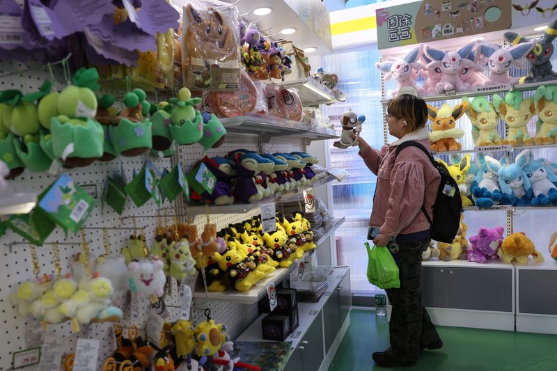A customer shops for a stuffed toy, at a pop-up store of Japanese animated series "Pokemon", in a shopping mall in Beijing, China November 18, 2025. REUTERS/Tingshu Wang