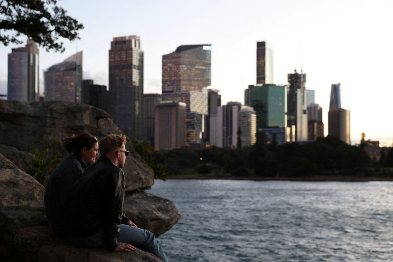 People sit and watch the sunset over the Central Business District (CBD) skyline in Sydney, Australia, July 10, 2025. REUTERS/Hollie Adams