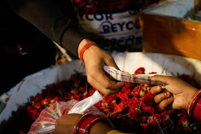 A vendor hands a currency note to a customer at a wholesale market in New Delhi, India, May 2, 2025. REUTERS/Priyanshu Singh