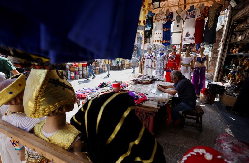 A vendor waits for customers near handmade traditional souvenir clothes displayed for sale, at a popular tourist area of the al-Hussein and Al-Azhar districts, in the capital city of Cairo, Egypt, July 10, 2023. REUTERS/Amr Abdallah Dalsh