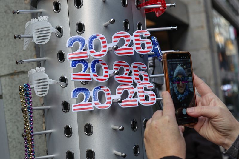 A person photographs novelty glasses shaped like "2026" featuring U.S. flag designs on display at a vendor stall ahead of New Year's Eve celebrations, in Times Square, New York City, U.S., December 30, 2025. REUTERS/Tyrone Siu