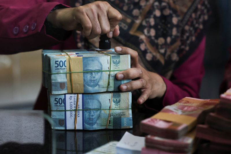 A teller prepares rupiah bank notes at a money changer in Jakarta, Indonesia, April 9, 2025. Picture taken through glass. REUTERS/Willy Kurniawan