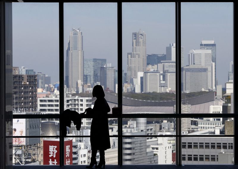 FILE PHOTO: A woman is silhouetted against a window overlooking skyscrapers at Shinjuku district, at a high-rise building in Tokyo, Japan, March 18, 2016. REUTERS/Issei Kato/File Photo