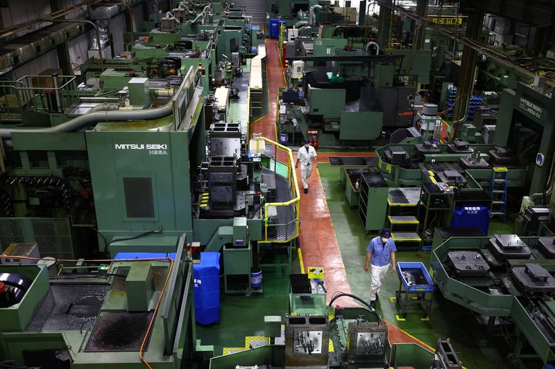 Workers walk between precision-machining machines for automotive parts inside a factory at Kyowa Industrial Co. in Takasaki, Gunma Prefecture, Japan April 11, 2025.  REUTERS/Issei Kato