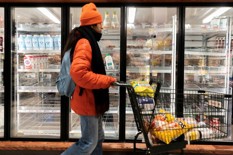 FILE PHOTO: A shopper walks past a partially empty dairy section at a grocery store ahead of an expected winter storm spreading across the United States, in Washington, D.C., U.S., January 24, 2026. REUTERS/Nathan Howard/File Photo