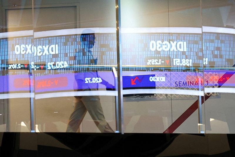 FILE PHOTO: A person walks past a glass window reflecting an electronic board showing stock market index at the Indonesia Stock Exchange (IDX) in Jakarta, Indonesia, February 2, 2026. REUTERS/Willy Kurniawan/File Photo