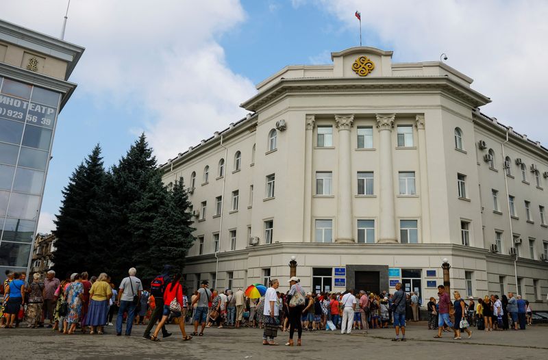 Local residents gather to receive financial aid during Ukraine-Russia conflict in the Russia-controlled city of Kherson, Ukraine July 25, 2022. REUTERS/Alexander Ermochenko/File Photo