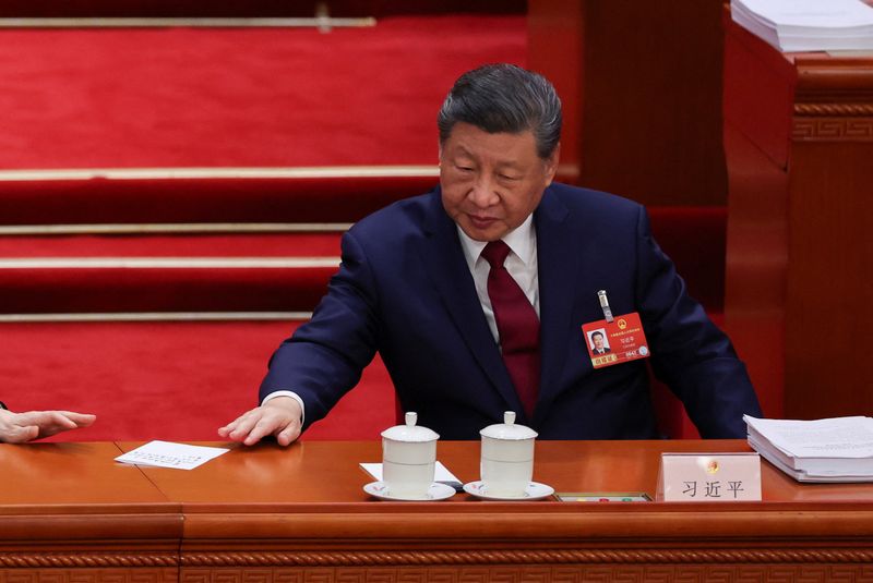 Chinese President Xi Jinping passes a paper to Chinese People's Political Consultative Conference (CPPCC) Chairman Wang Huning (not pictured) during the opening session of the National People's Congress (NPC) at the Great Hall of the People in Beijing, China, March 5, 2026. REUTERS/Florence Lo/Pool