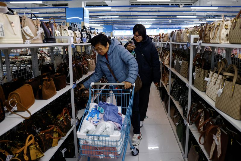 Customers shop for bags at the Wankelai store in Beijing, China February 27, 2025. REUTERS/Tingshu Wang
