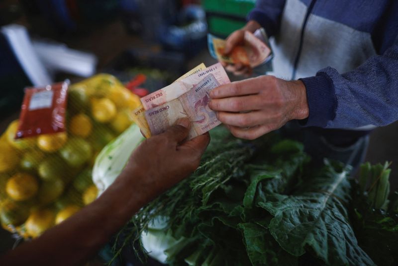 A man pays a vendor at a fruit stand, at a supply centre (CEASA) in Brasilia, Brazil May 9, 2023. REUTERS/Adriano Machado