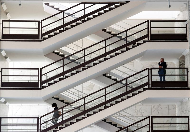 FILE PHOTO: A man talks on the phone as a woman walks down the stairs at Palazzo delle Esposizioni in Rome, Italy April 26, 2023. REUTERS/Remo Casilli/File Photo