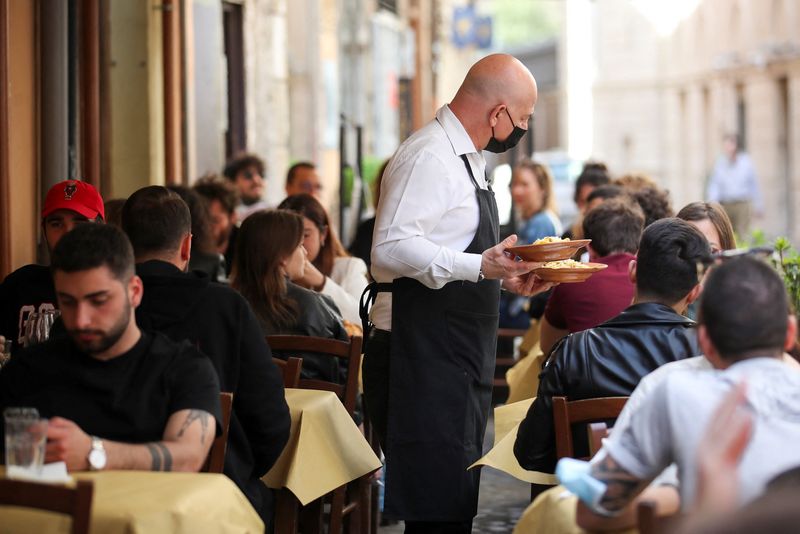 A waiter carries food during lunch on a terrace of a restaurant in Rome, Italy, April 26, 2021. REUTERS/Yara Nardi