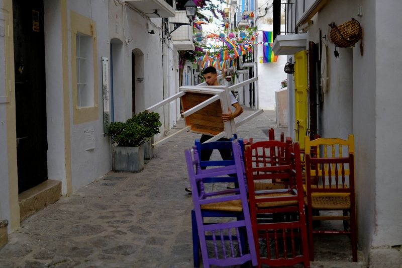 FILE PHOTO: A waiter arranges the tables at a restaurant near Playa d'en Bossa beach in Ibiza, Spain, June 13, 2025. REUTERS/Nacho Doce/File Photo