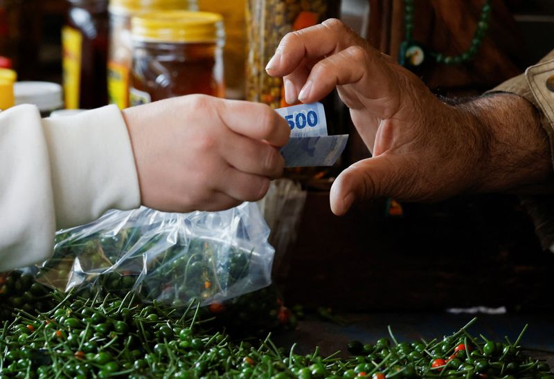 A customer pays the vendor at a market stall as inflation rises in early January, driven by new taxes and higher import tariffs, with cigarettes and soft drinks among the biggest price gainers, in Monterrey, Mexico, January 22, 2026. REUTERS/Daniel Becerril/File Photo