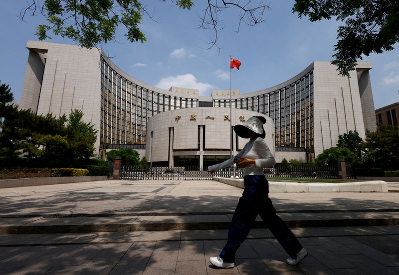 FILE PHOTO: A person walks past the headquarters of the People's Bank of China, in Beijing, China May 7, 2025. REUTERS/Tingshu Wang