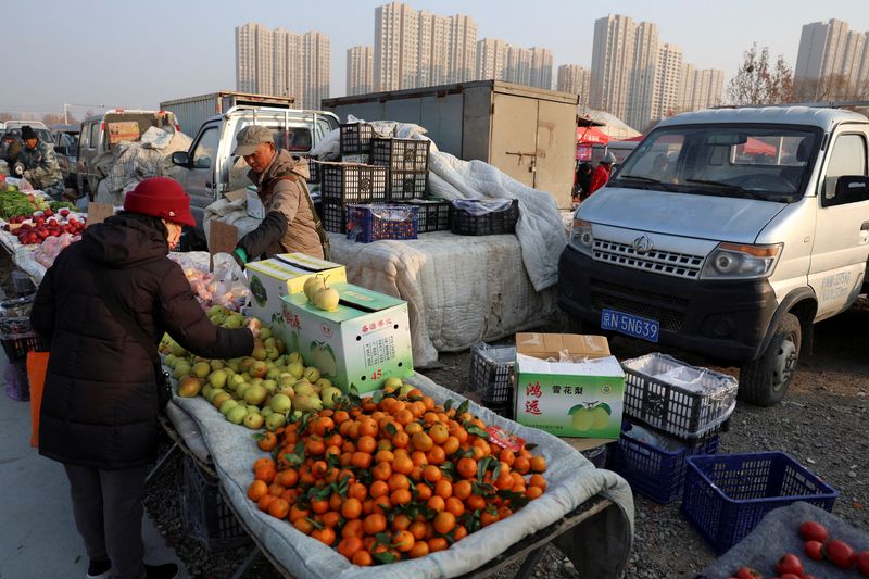 FILE PHOTO: A fruit vendor attends to a customer at an outdoor market in Beijing, China January 12, 2024. REUTERS/Florence Lo/File Photo