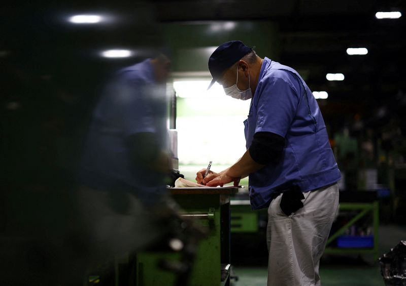 A worker writes next to a precision-machining machine for automotive parts inside a factory at Kyowa Industrial Co. in Takasaki, Gunma Prefecture, Japan April 11, 2025.  REUTERS/Issei Kato