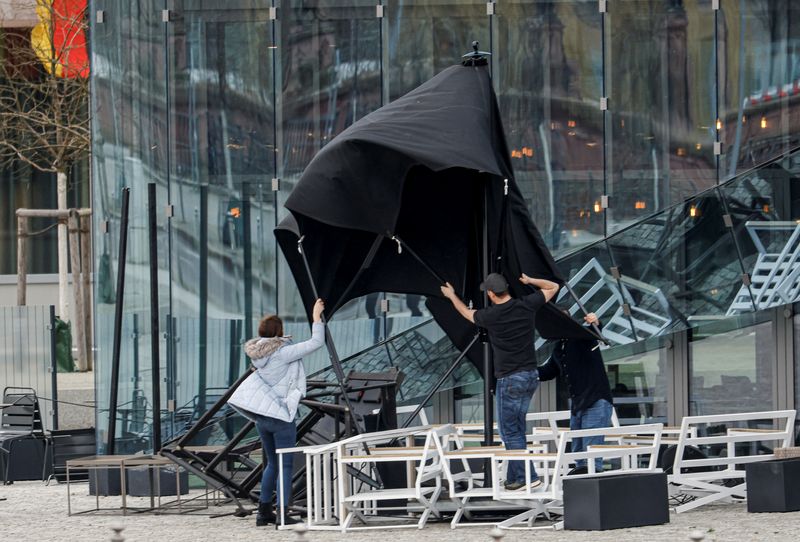 People hold a patio umbrella in a strong wind outside a restaurant in Berlin, Germany February 17, 2022. REUTERS/Michele Tantussi