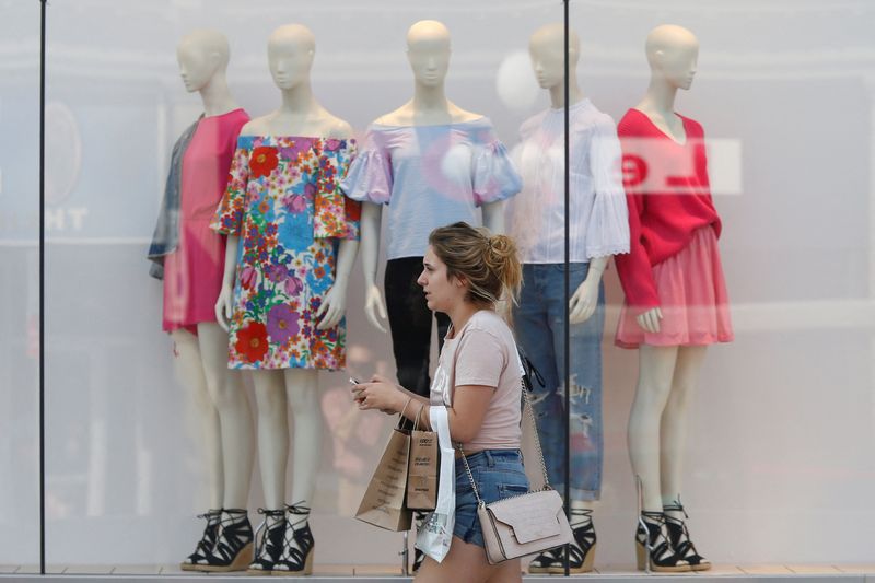 FILE PHOTO: A woman carries shopping bags while walking past a window display outside a retail store in Ottawa, Ontario, Canada, July 21, 2017. REUTERS/Chris Wattie/File Photo