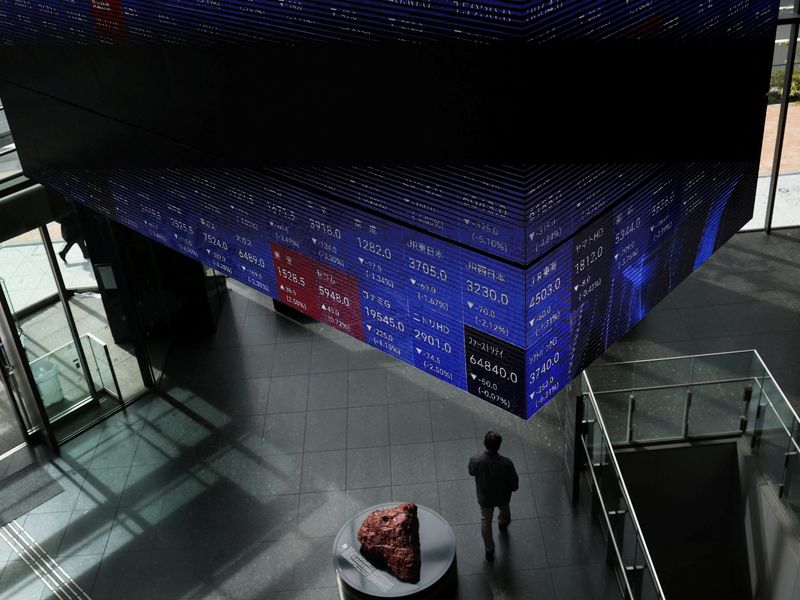 A visitor walks past Japan's Nikkei stock prices quotation board inside a conference hall in Tokyo, Japan March 4, 2026. REUTERS/Issei Kato/File Photo