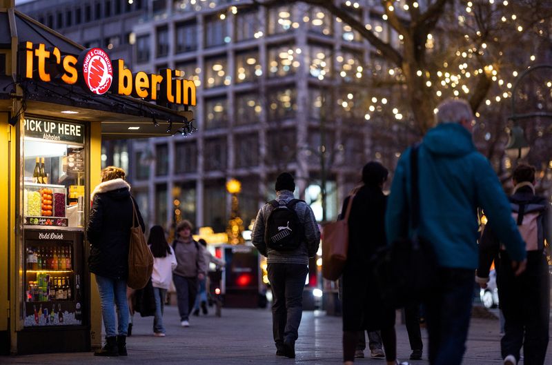 People walk next to a Doner kebab and Currywurst booth at Kurfuerstendamm shopping street during Christmas season in Berlin, Germany, December 18, 2023.  REUTERS/Lisi Niesner