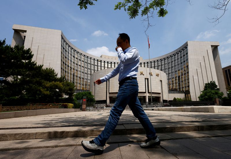FILE PHOTO: A man walks past the headquarters of the People's Bank of China, in Beijing, China May 7, 2025. REUTERS/Tingshu Wang/File Photo