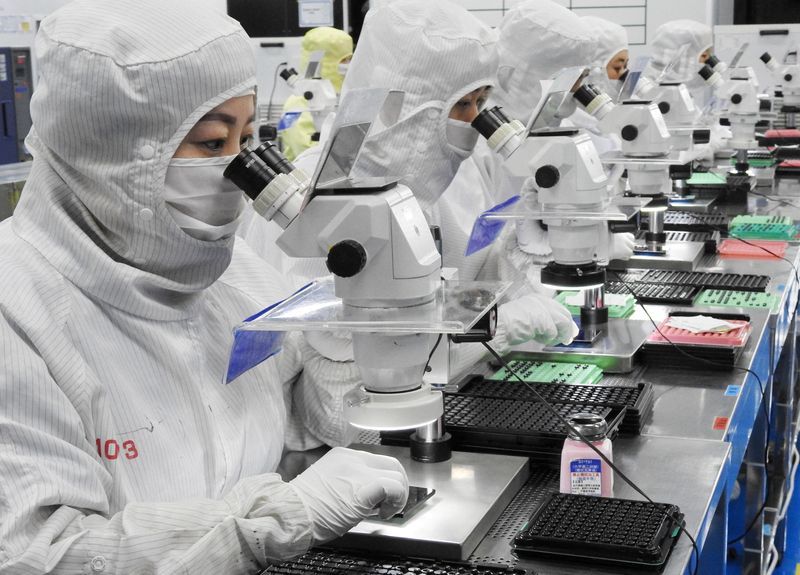 FILE PHOTO: Employees work on a production line manufacturing camera lenses for cellphones at a factory in Lianyungang, Jiangsu province, China April 30, 2019. China Daily via REUTERS/File Photo