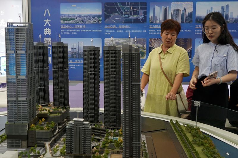 An agent attends to a customer near a scale model of residential buildings at a property fair in Shenzhen, Guangdong province, China October 12, 2024. REUTERS/Nicoco Chan/File Photo