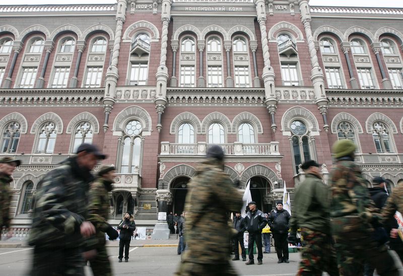 Activists of the Right Sector political party walk in front of the building of Ukraine's central bank during an anti-government rally in Kiev February 25, 2015. The value of Ukraine's free-falling hryvnia was in limbo on Wednesday after the central bank banned nearly all commercial currency trading until the end of the week, a decision denounced by the prime minister as bad for the economy.  REUTERS/Valentyn Ogirenko (UKRAINE - Tags: CIVIL UNREST POLITICS BUSINESS)