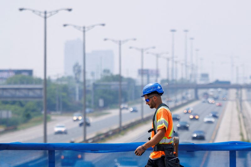 A construction worker walks long a barricade on Islington Avenue in Toronto, Ontario, Canada, July 14, 2025. REUTERS/Carlos Osorio