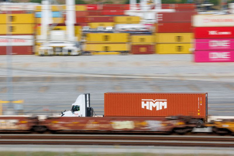 FILE PHOTO: A trucker drives his cargo past shipping containers at the West Basin Container Terminal at the Port of Los Angeles in Los Angeles, California, U.S., February 24,  2026.  REUTERS/Mike Blake/File Photo