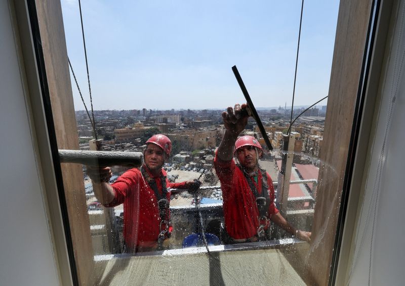 Egyptian workers clean the glass exterior of a building in Cairo, Egypt, May 6, 2026. REUTERS/Mohamed Abd El Ghany