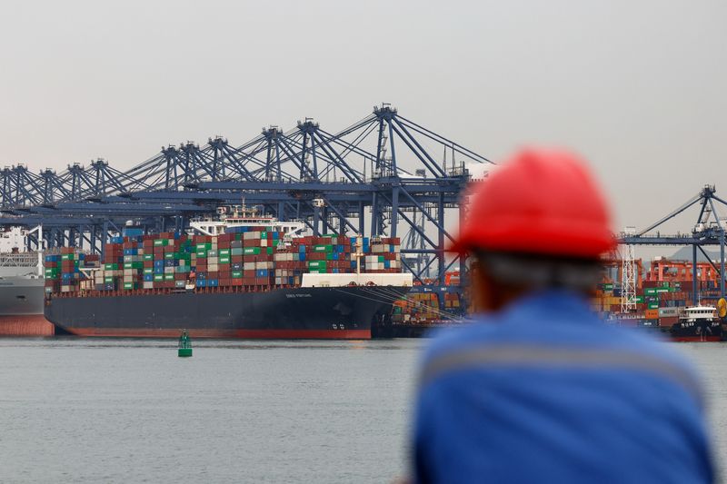 A worker looks on near a cargo ship carrying containers at the Yantian port in Shenzhen, Guangdong province, China May 9, 2025. REUTERS/Tingshu Wang